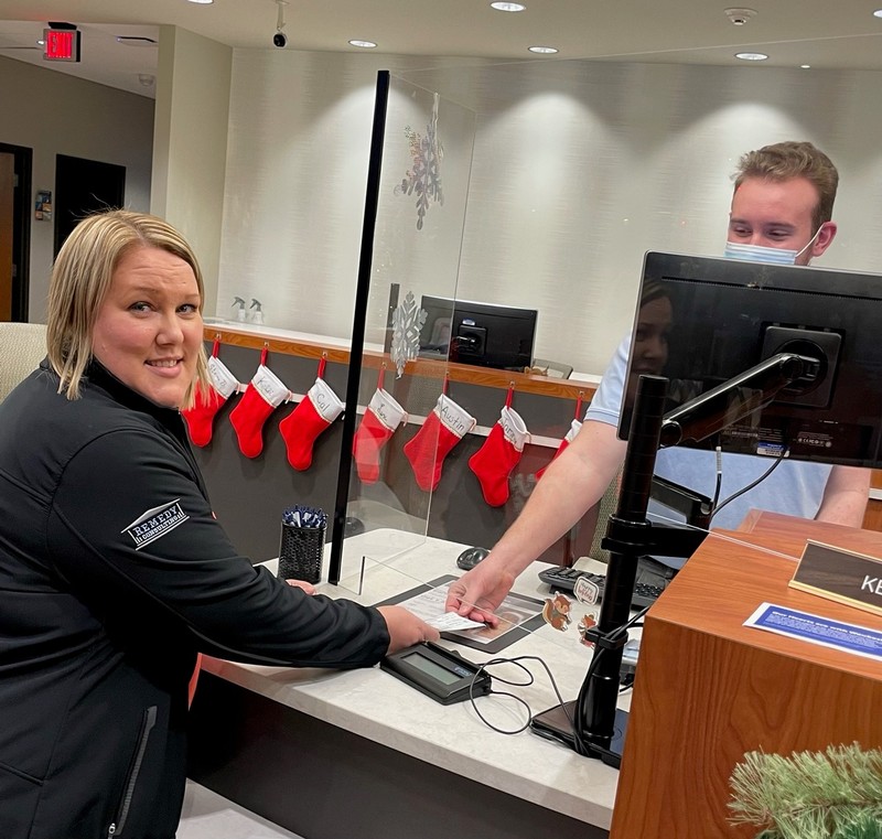 Karen Lowerr of Remedy Consulting presenting check to Landmark Credit Union teller Kevin for the United for Waukesha Community Fund to help Waukesha Parade tradegy victims in 2021.