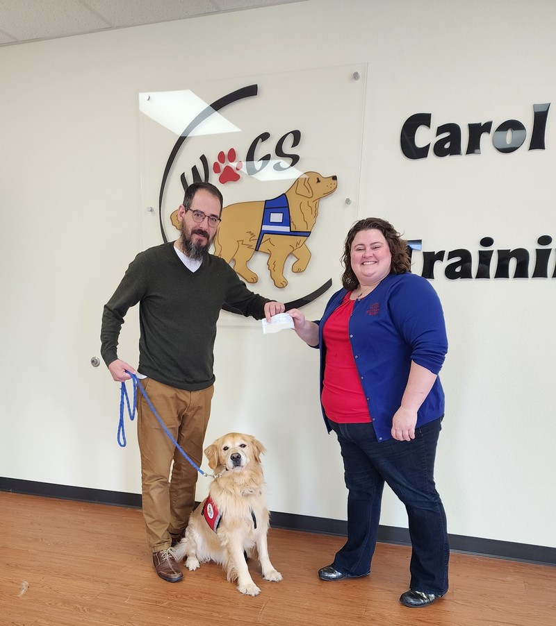 Bankers’ Bank’s Ms. Nicole Schiesser presenting Remedy Consulting’s donation to Mr. Aaron Becker, Executive Director of WAGS and one his trainees, the golden retriever Austin. 