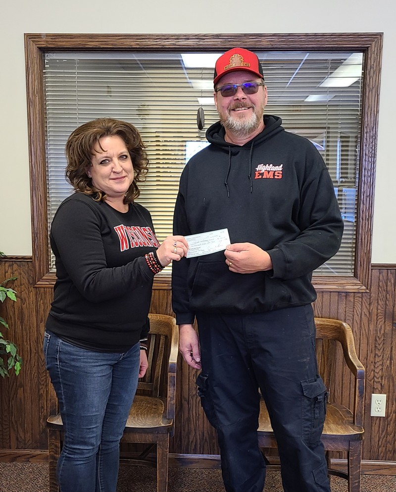 The photo is showing Highland State Bank Vice President, Jennifer Biba, presenting the check to Neil Michek, President of the Highland Ambulance Service in December 2023.